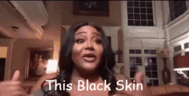 a woman is giving a thumbs up in a living room and says `` this black skin '' .