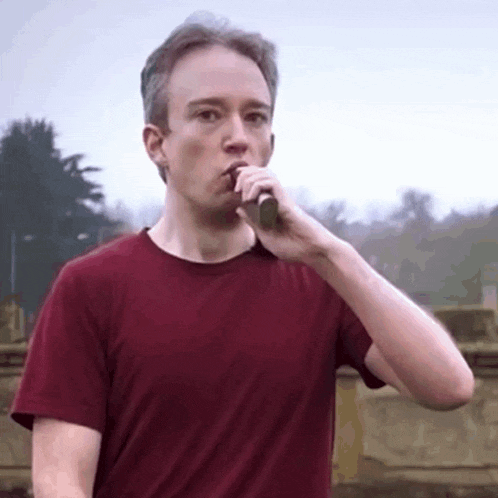 a man in a red shirt is drinking from a bottle