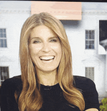 a woman in a black shirt smiles in front of a white house