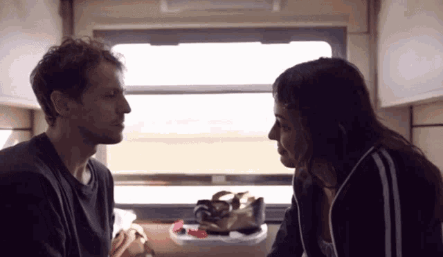a man and a woman looking at each other in a room