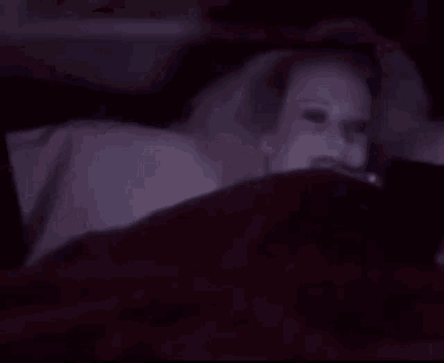 a woman with glowing eyes is smiling while laying in bed .