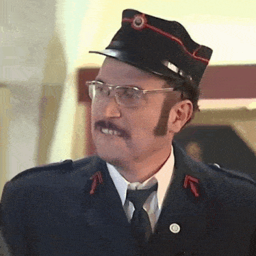 a man with a mustache and glasses is wearing a black hat with a red stripe