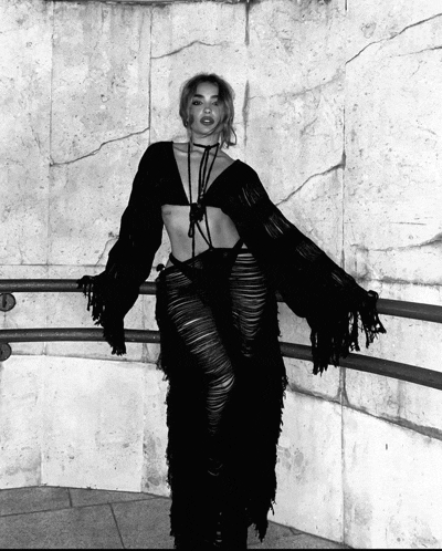 a black and white photo of a woman wearing a black outfit