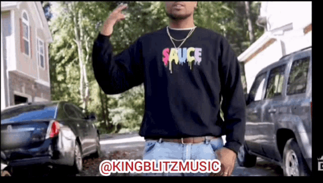 a man wearing a black shirt that says sauce on it