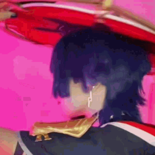 a close up of a person 's head with a red hat on a pink background .