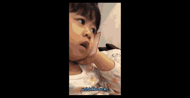a little girl is holding a piece of paper in her hand and making a funny face .