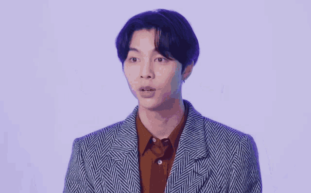 a young man with purple hair is wearing a plaid jacket and brown shirt