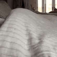 a close up of a bed with a striped blanket on it