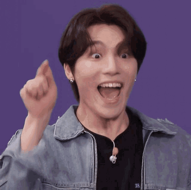 a man in a denim jacket is making a funny face with his mouth open