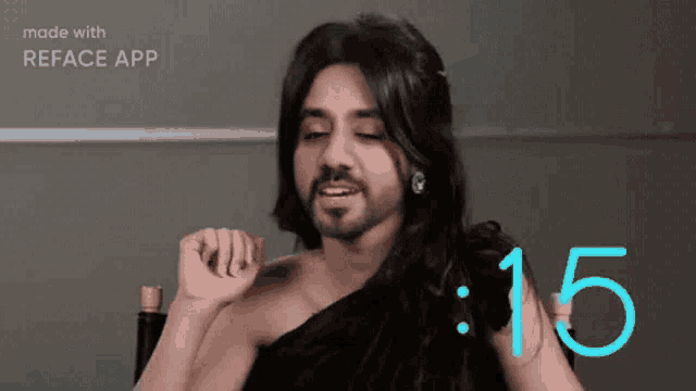 a man with long hair and a beard is wearing a black one shoulder top and earrings ..