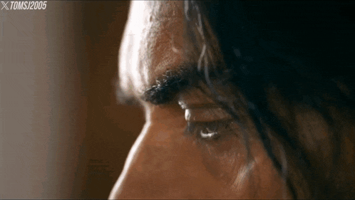 a close up of a man 's eye with a tear coming out of his eye .