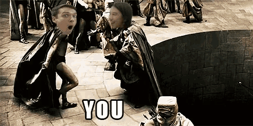 a man in a cape stands in front of a group of people and says " you " on the bottom