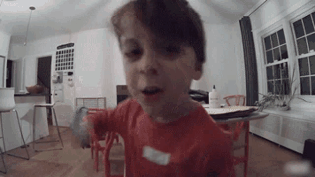a young boy in an orange shirt is standing in a room
