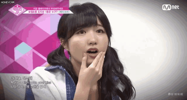 a girl with pigtails is covering her mouth with her hand in front of a mnet logo ..