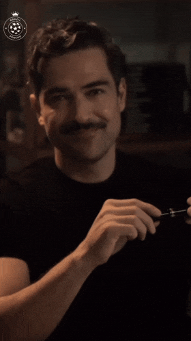 a man with a mustache is smiling and holding a tool with a crown on it