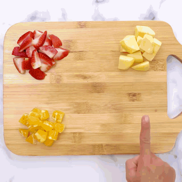 a wooden cutting board with strawberries pineapples and blueberries on it