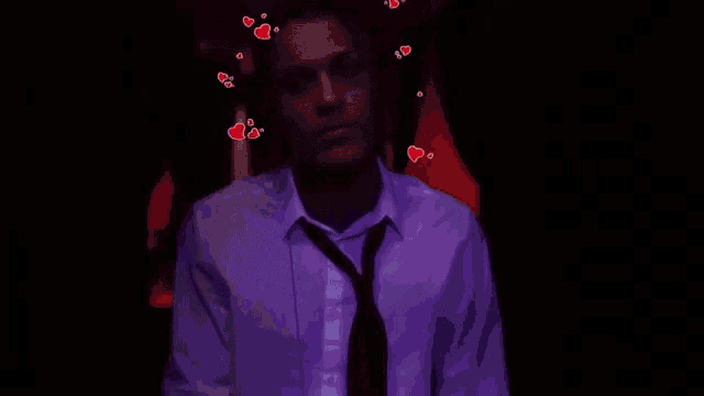 a man in a white shirt and tie is standing in a dark room with hearts flying around his head .