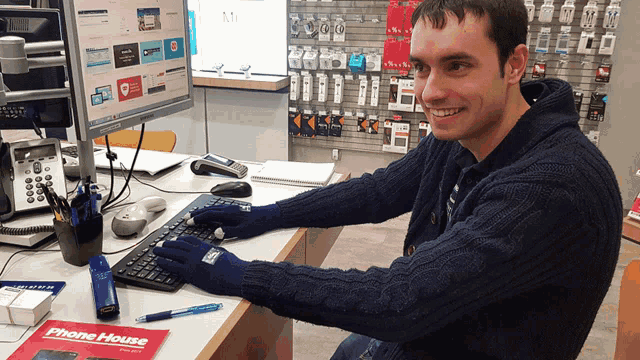 a man wearing blue gloves is typing on a keyboard in front of a phone house magazine