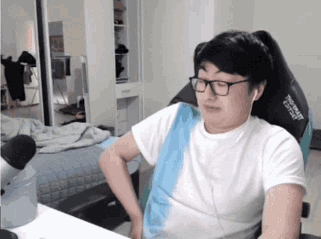 a man wearing glasses and headphones sits in a chair that says " ultimate " on the back