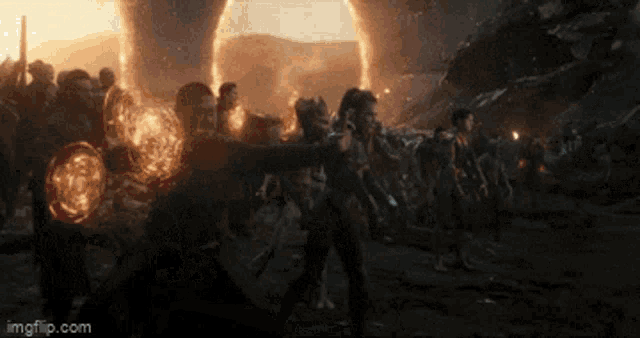 a group of people are standing in front of a large explosion and a watermark that says imgflip.com