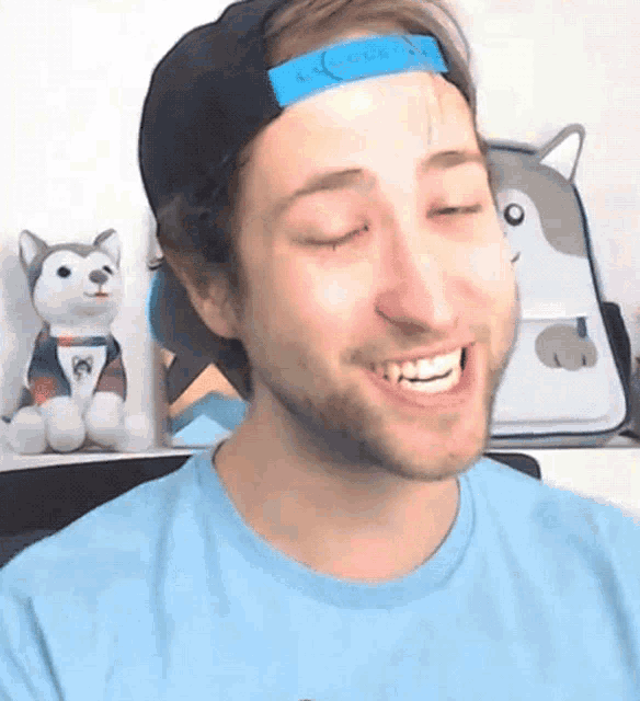 a man wearing a blue shirt and a hat is smiling