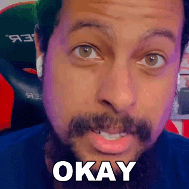 a man with a beard and ear buds is saying okay .
