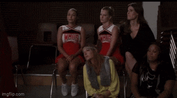 a group of cheerleaders are sitting next to each other in chairs .