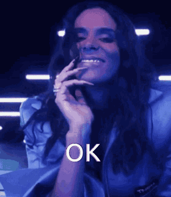 a woman in a blue jacket is smiling and the word ok is on the bottom