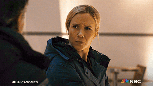a woman in a blue jacket is talking to a man in a dark room with a nbc logo in the corner