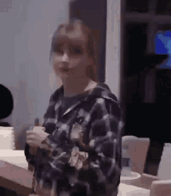 a woman in a plaid shirt is standing in front of a table with a glass of water .