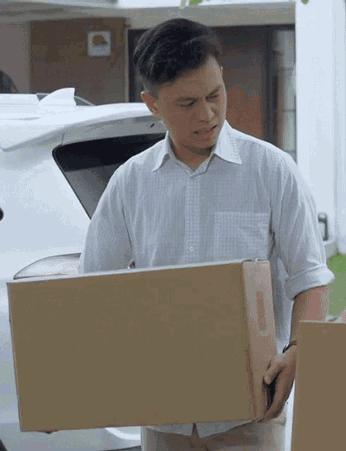 a man in a white shirt is holding a cardboard box with a sticker on it that says ' fragile '
