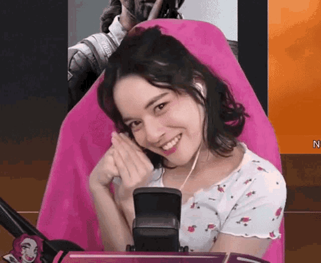 a woman is sitting in a pink chair with a microphone in front of her and smiling .