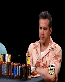 a man sits at a table with bottles of hot sauce on it