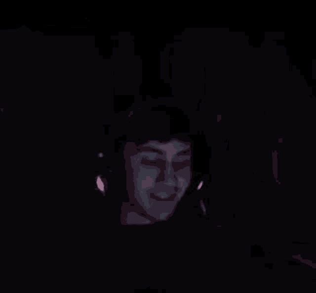 a blurry picture of a person 's face in the dark with red lights on their ears .