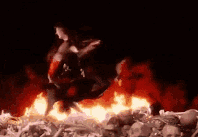 a woman is standing in front of a pile of skeletons in a fire .