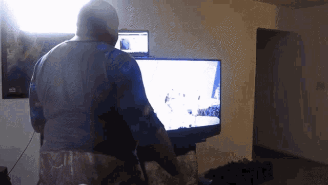 a man in a blue shirt is standing in front of a television