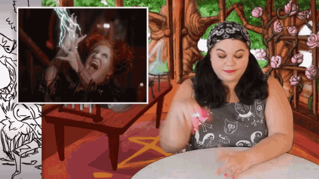 a woman sitting at a table in front of a picture of a witch