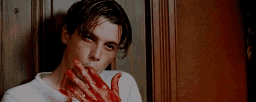 a man with blood on his face and hands covering his mouth