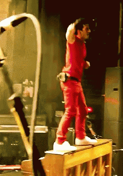 a man in red is standing on a piano