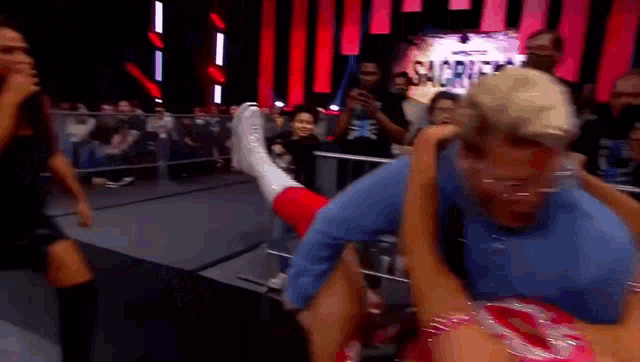 a woman is being lifted on a man 's shoulders in a wrestling ring .