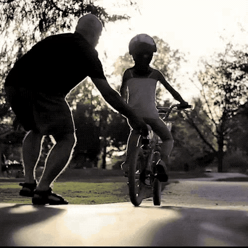 a man helps a young girl ride a bike
