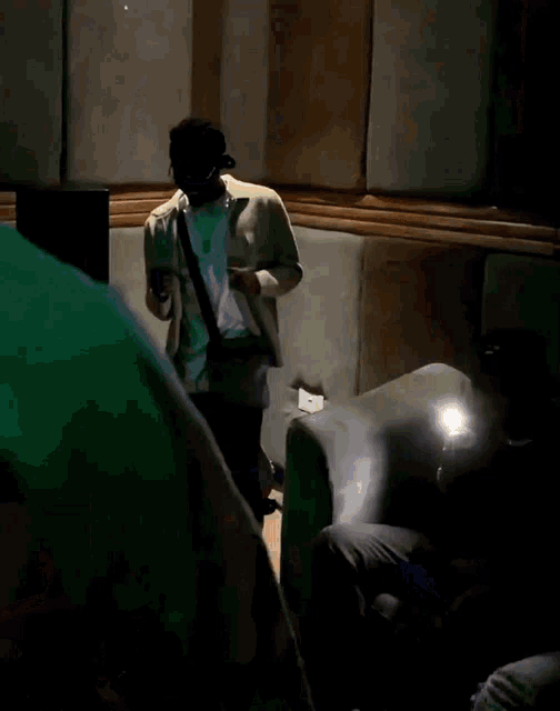 a man is standing in a dark room with a guitar