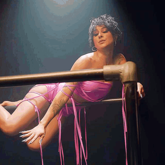 a woman is laying on a railing in a pink outfit