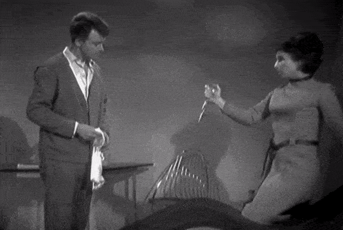 a black and white photo of a man and a woman holding a knife