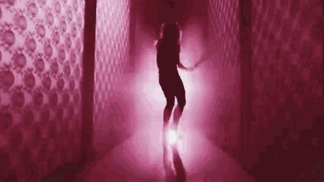 a woman is dancing in a pink room with a skull wallpaper .