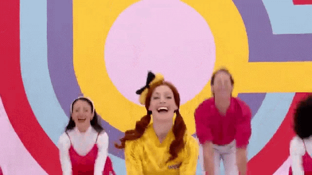 a group of people are dancing in front of a colorful background and a woman is laughing .