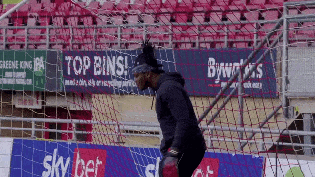 a soccer goalie stands in front of a sky bet sign