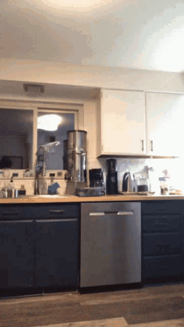 a kitchen with a stainless steel dishwasher and blue cabinets