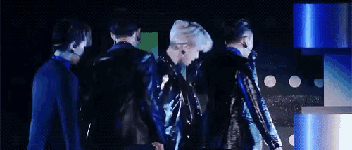 a group of men are standing next to each other on a stage in front of a blue background .
