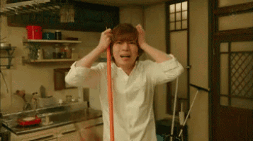 a man in a white shirt is holding a mop to his head .